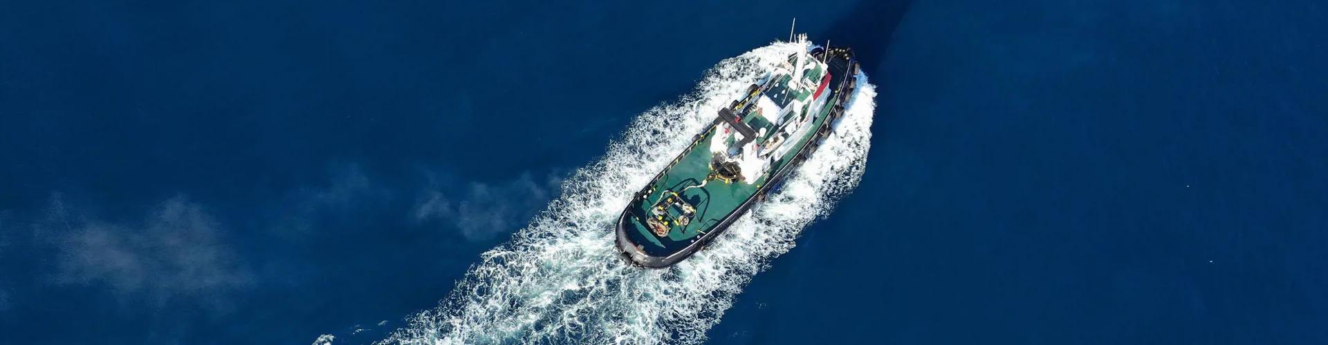 Aerial drone photo of tug boat cruising Mediterranean port