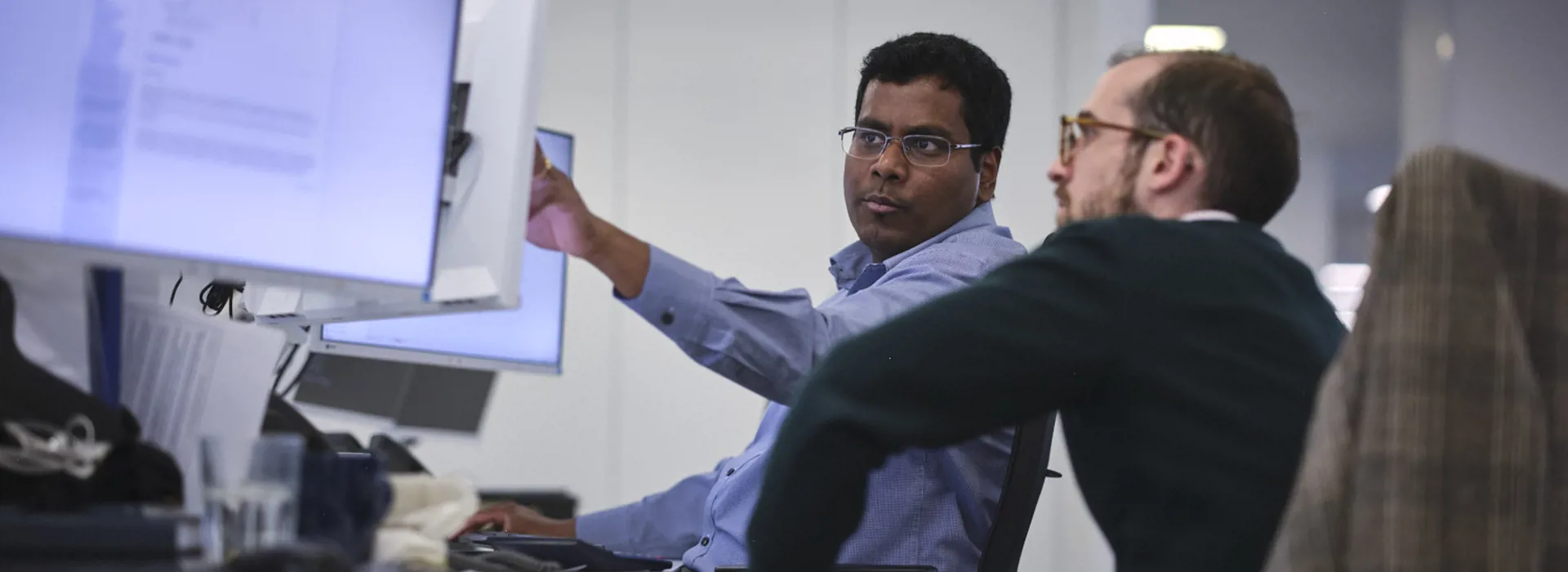 man pointing at his screen explaining to colleagues