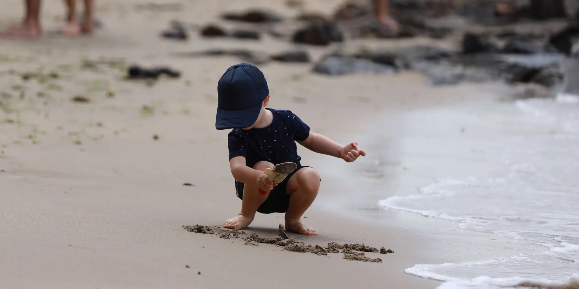 little boy playing with sand on a beach