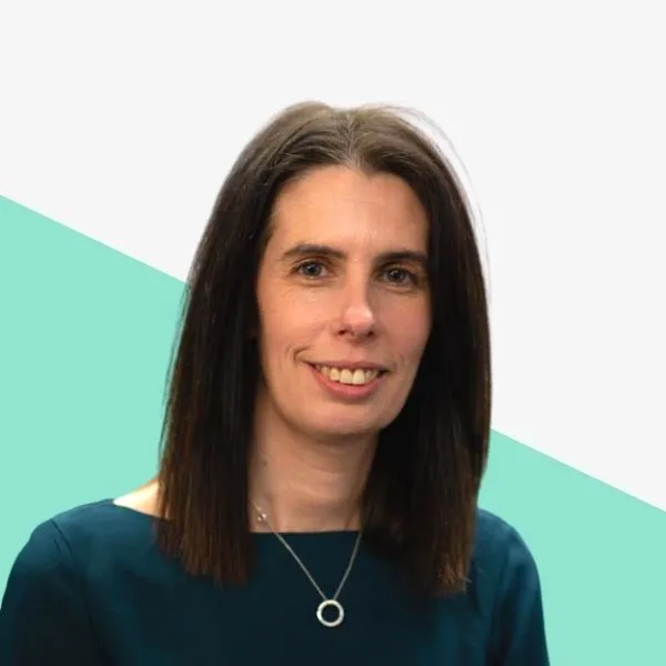 Smiling woman with dark hair in a dark top against a light background with a teal geometric shape.
