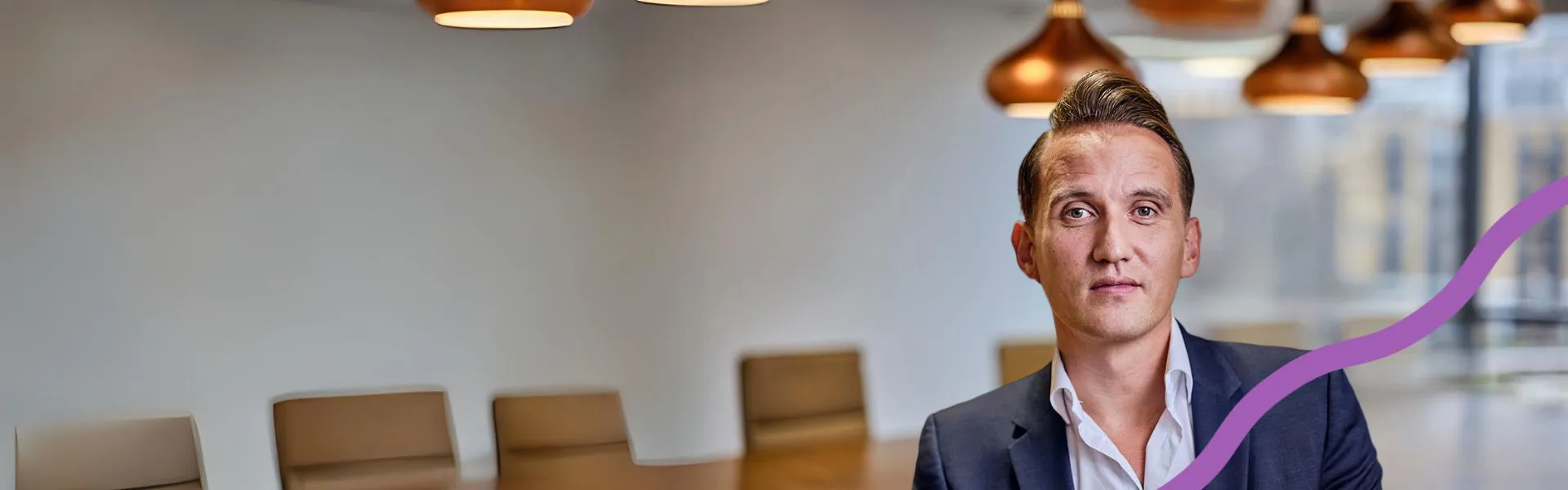 Man in a suit in a modern office setting.