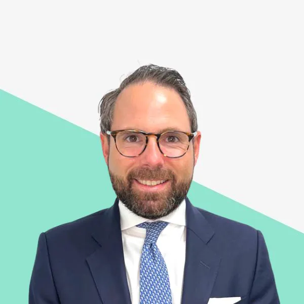 Smiling man in a suit against a geometric background.