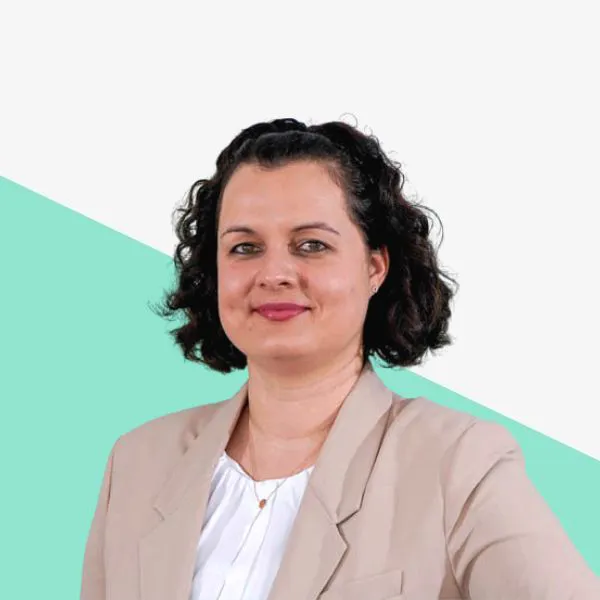 Woman with curly hair, wearing a light blazer.
