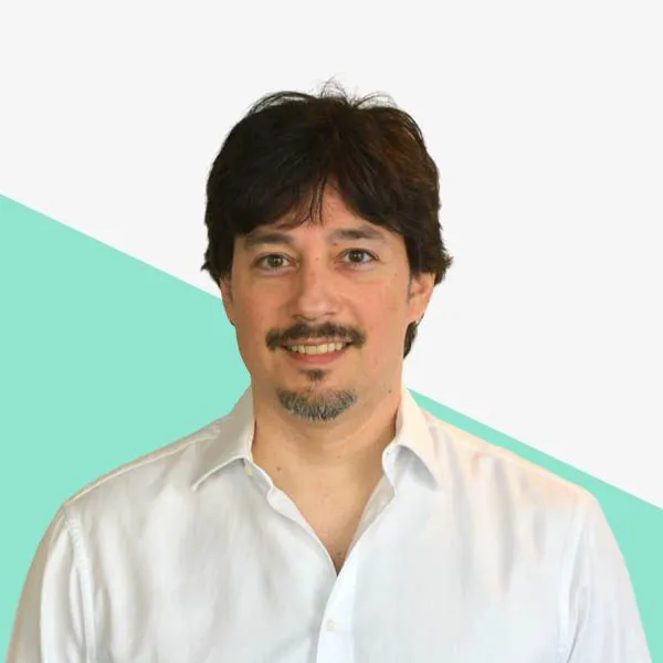Smiling man with dark hair in a white shirt.
