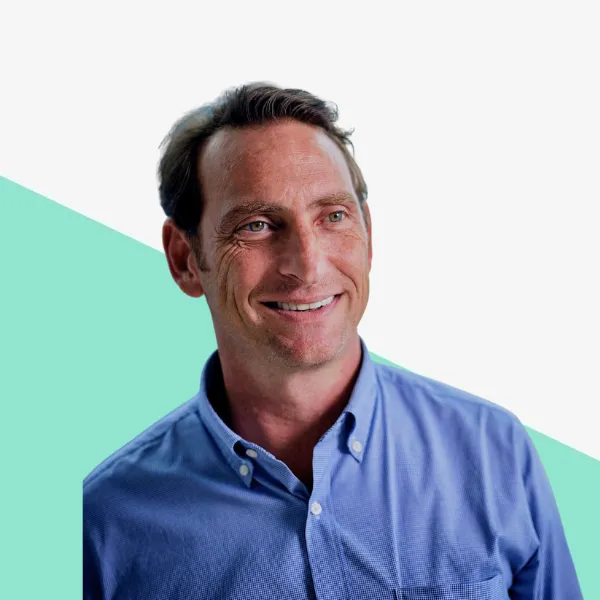 Smiling man in a blue shirt against a light background.