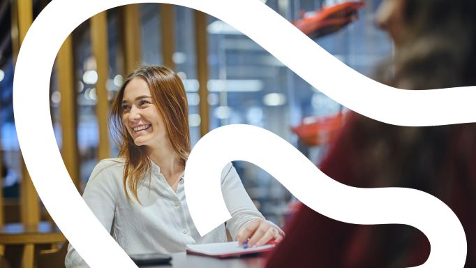 Smiling woman at a table with a notepad.