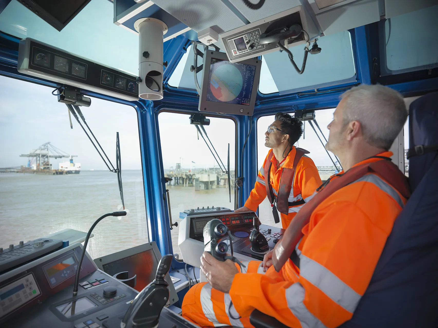 Tug workers wearing protective clothing steering tug