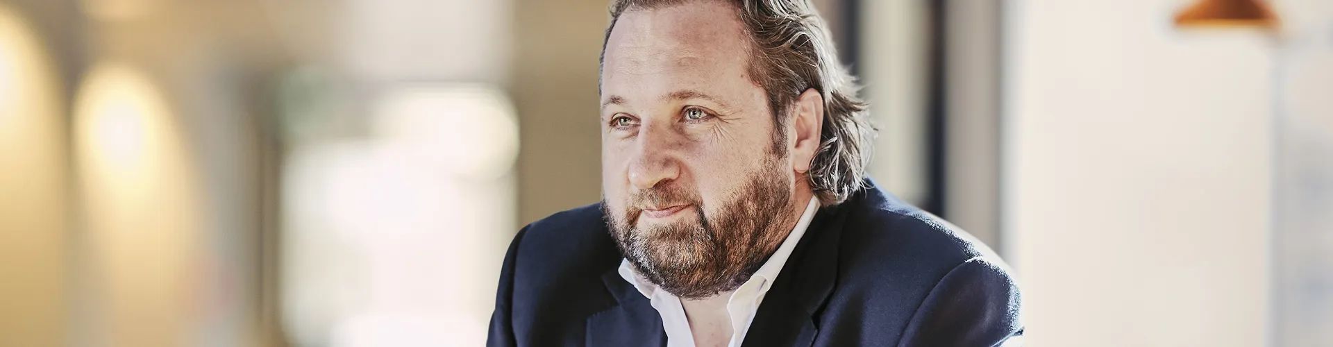 Man with beard in a suit sitting at a table.