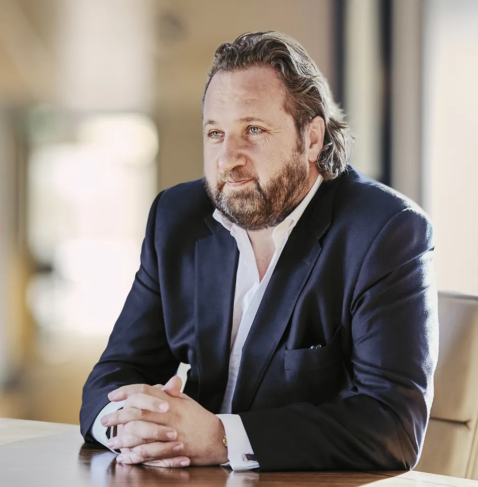 Man with beard in a suit sitting at a table.