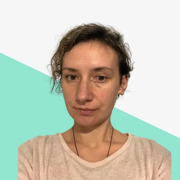 Person with curly hair, neutral expression, light background.