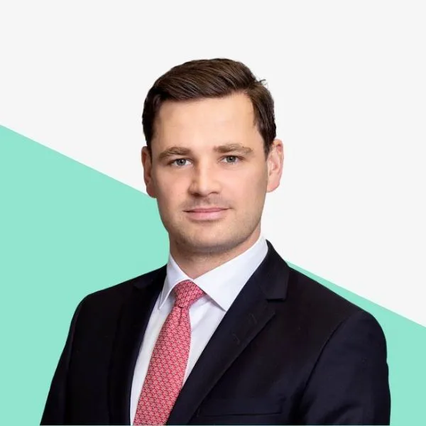 Man in a suit with a pink tie against a light background.