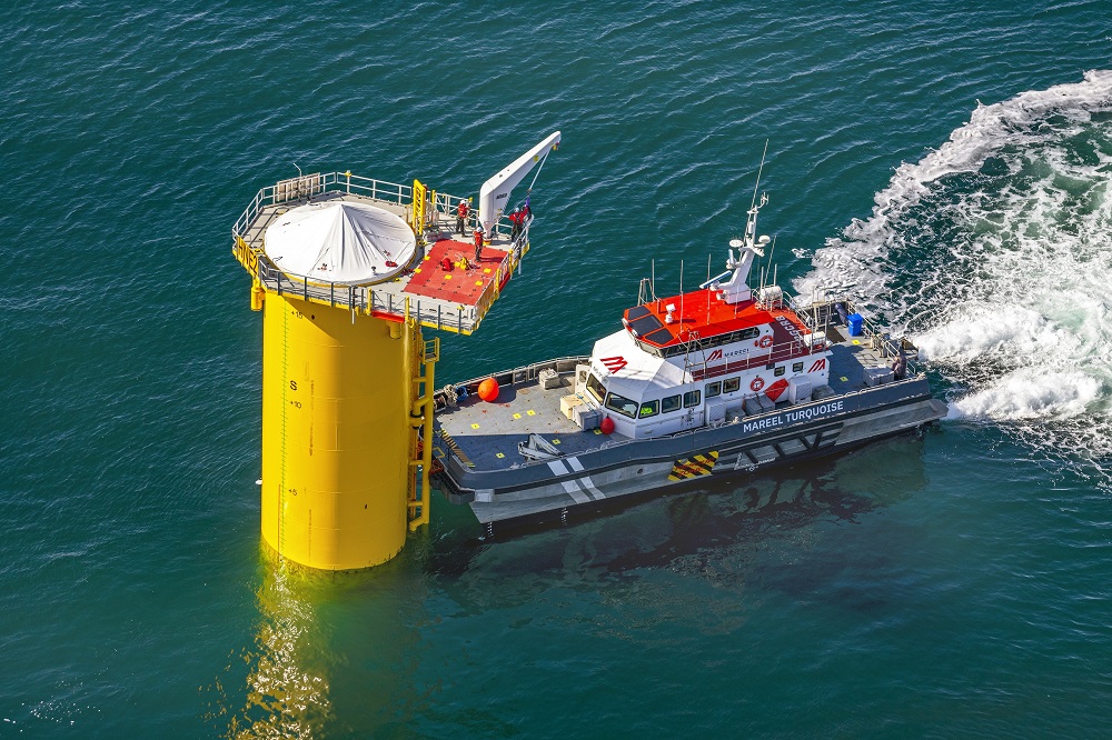 Boat near a yellow offshore platform in blue water.