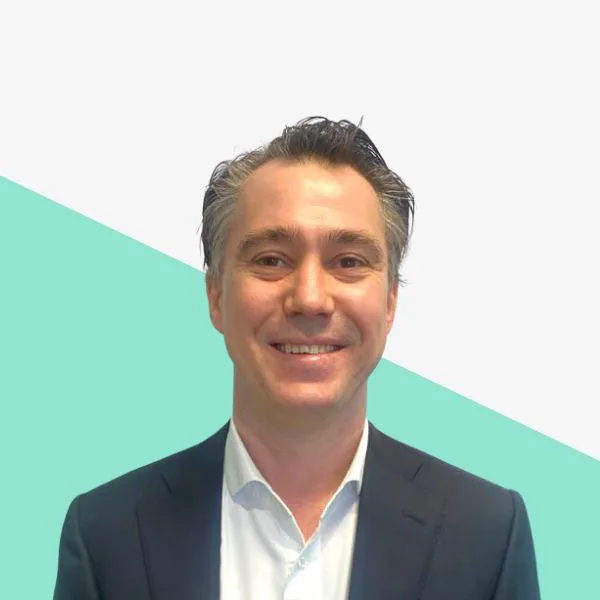 Smiling man in a suit against a geometric background.