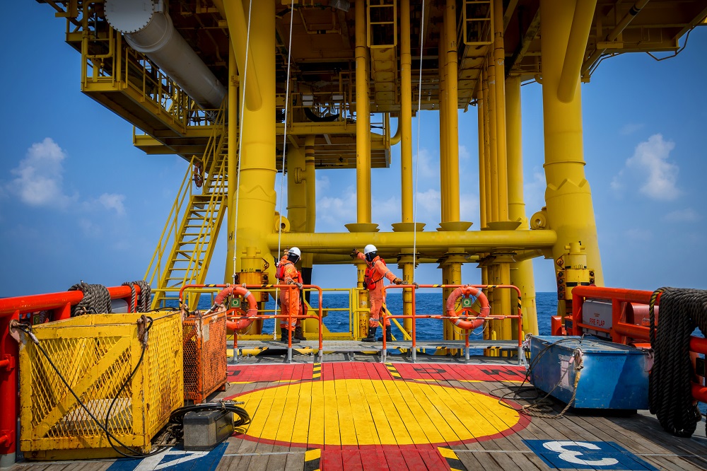 Two workers on a yellow offshore platform.