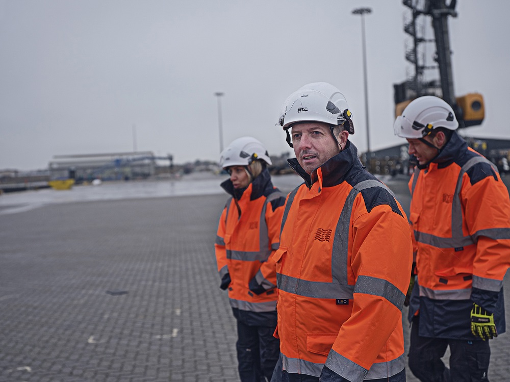 Three workers in uniform and helmets walking