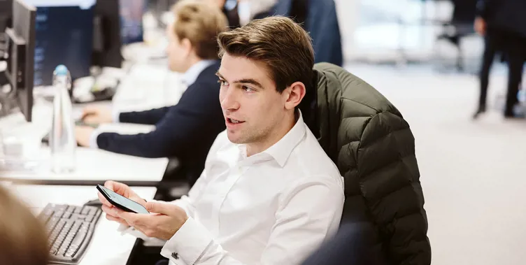man sitting at his desk talking with phone in hand