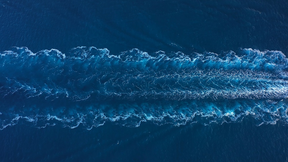 Aerial view of ocean waves and wake trails.