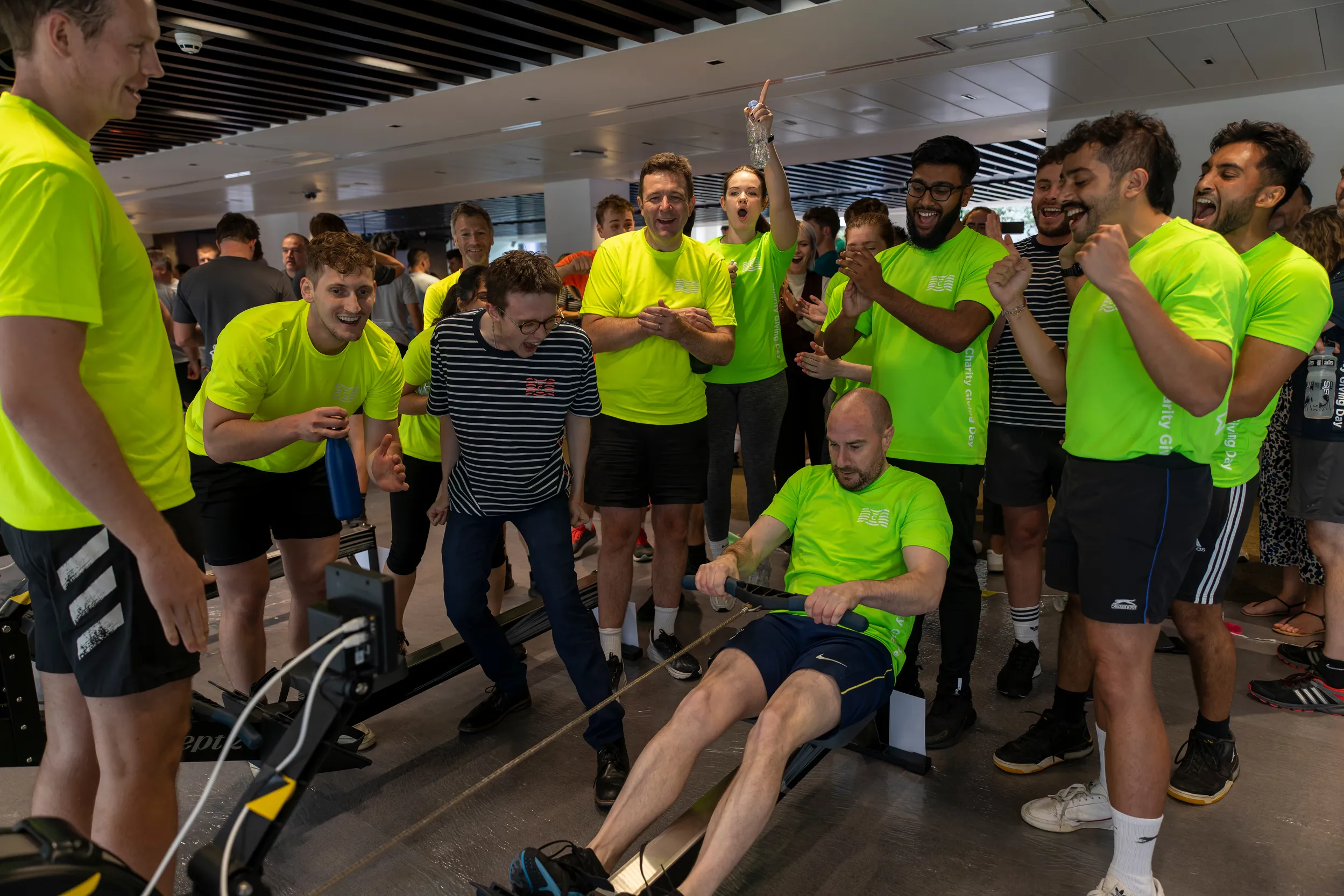 Group of people cheering on a rower in bright shirts.