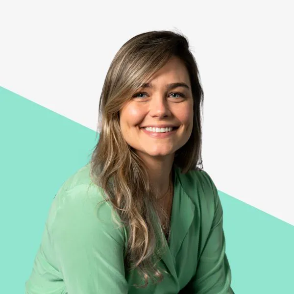 Smiling woman in a green blouse on a teal background.