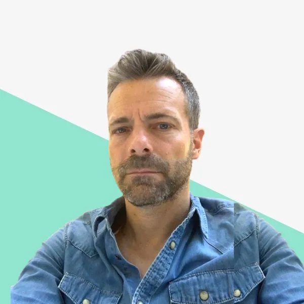 Man with beard in denim shirt on a geometric background.