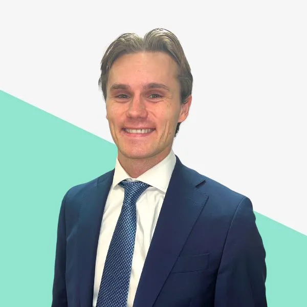 Smiling man in a suit against a light background.
