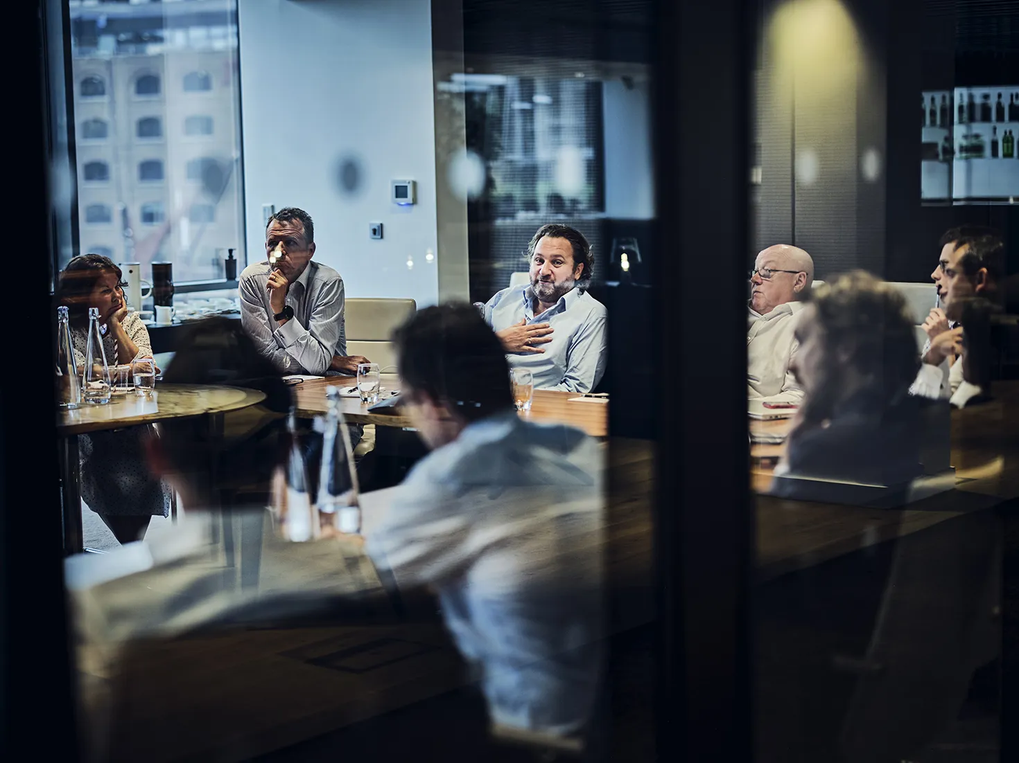 looking through a meeting room window at seniour employees