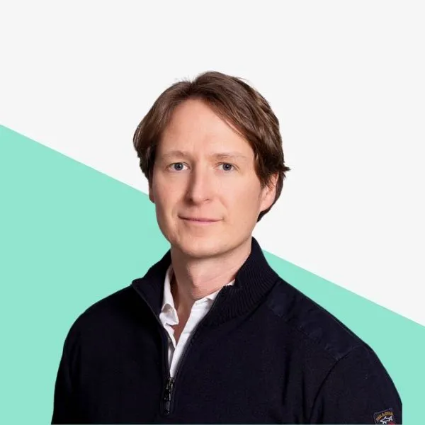 A man with shoulder-length hair, wearing a dark sweater.