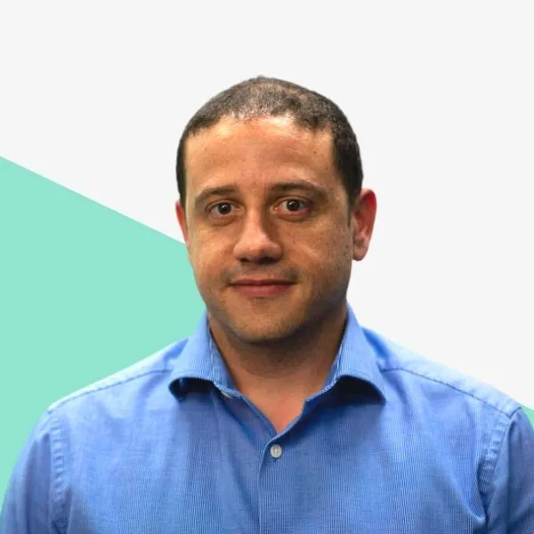 Man in a blue shirt, neutral expression, plain background.
