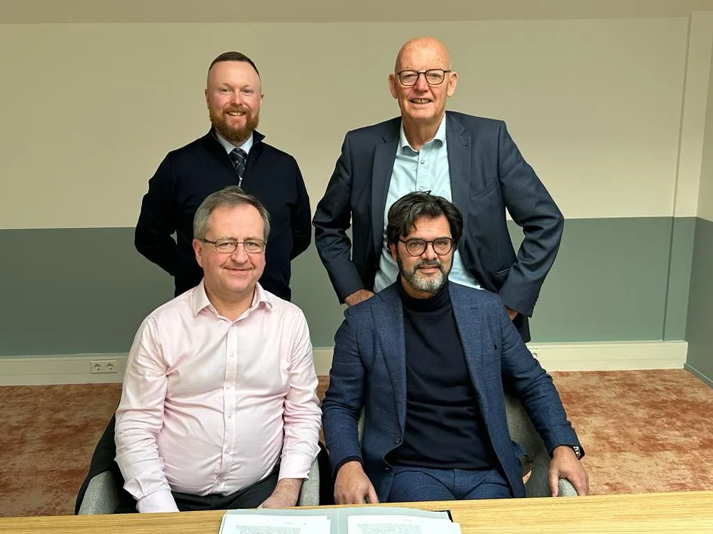 Four men posing for a photo in an office setting.
