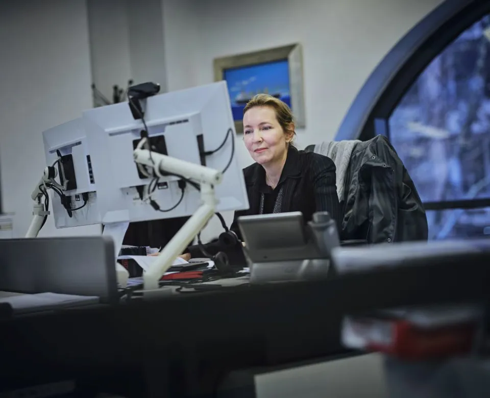 Woman working at a desk with dual monitors.