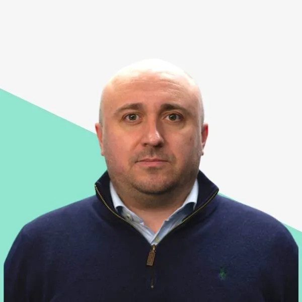 Bald man in a dark sweater against a light background.