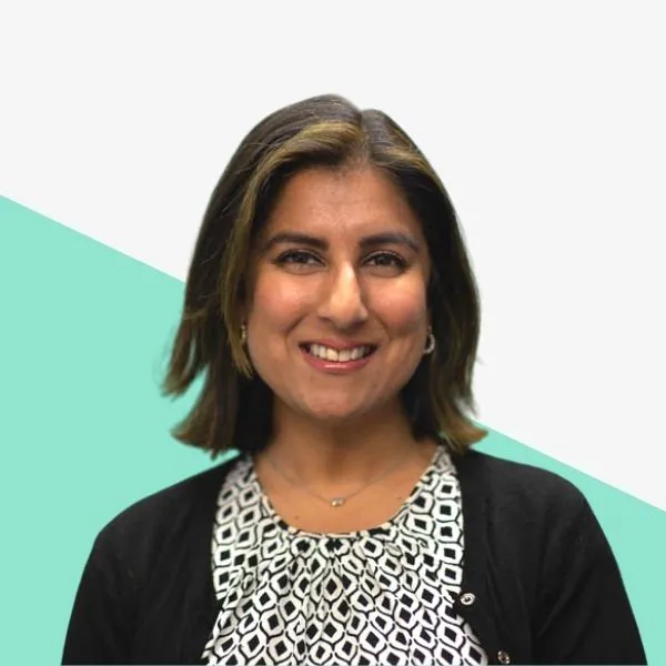 Smiling woman in a patterned top and black cardigan against a light background with a mint green shape.