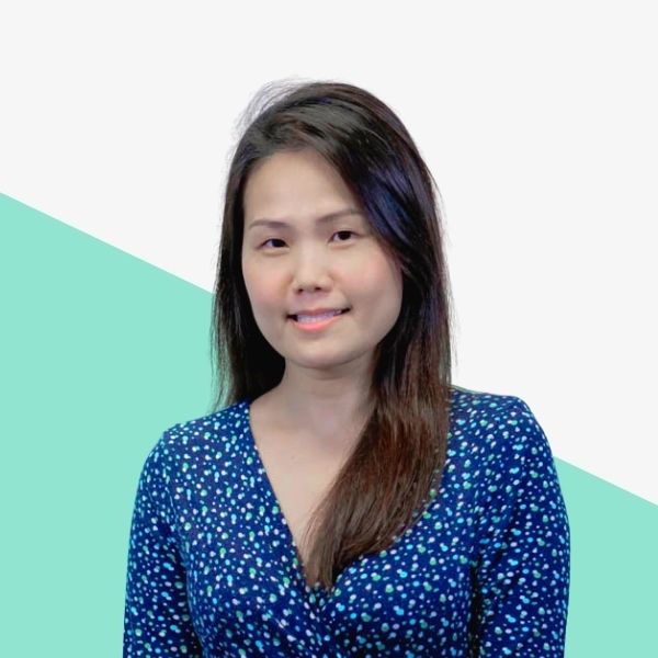 Smiling woman in a blue polka-dot dress against a light background with a green triangular design.