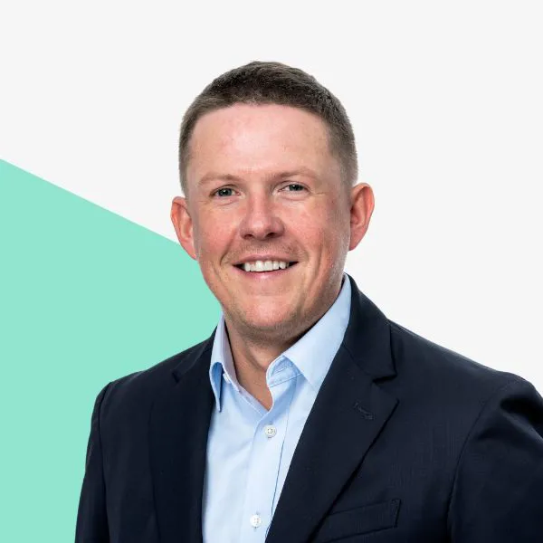 Smiling man in a suit against a minimalist background.