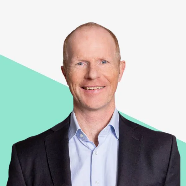 Smiling man in a suit with a light background.