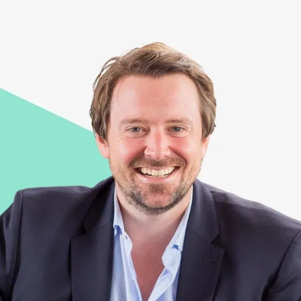 Smiling man in a suit against a light background.