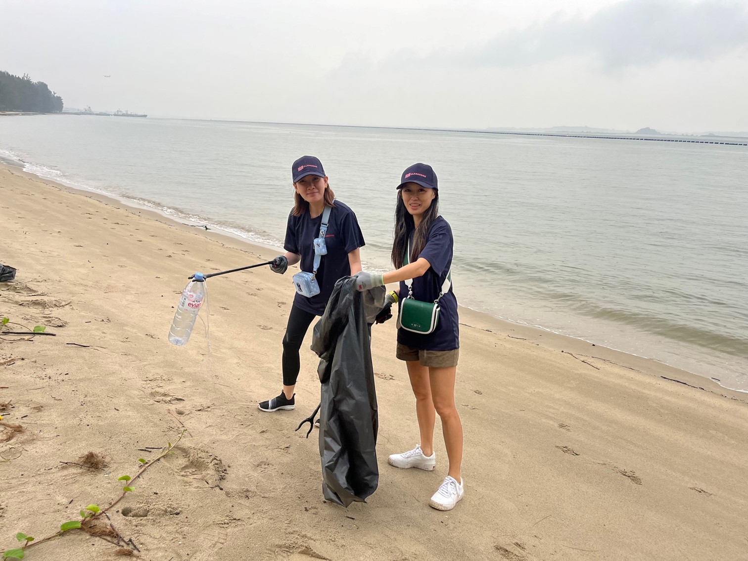 Two women cleaning a beach.