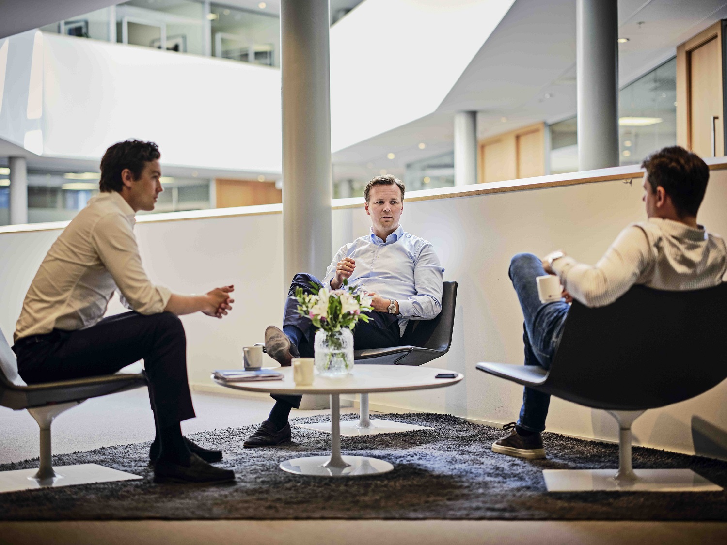 Three men seated in a modern office setting.