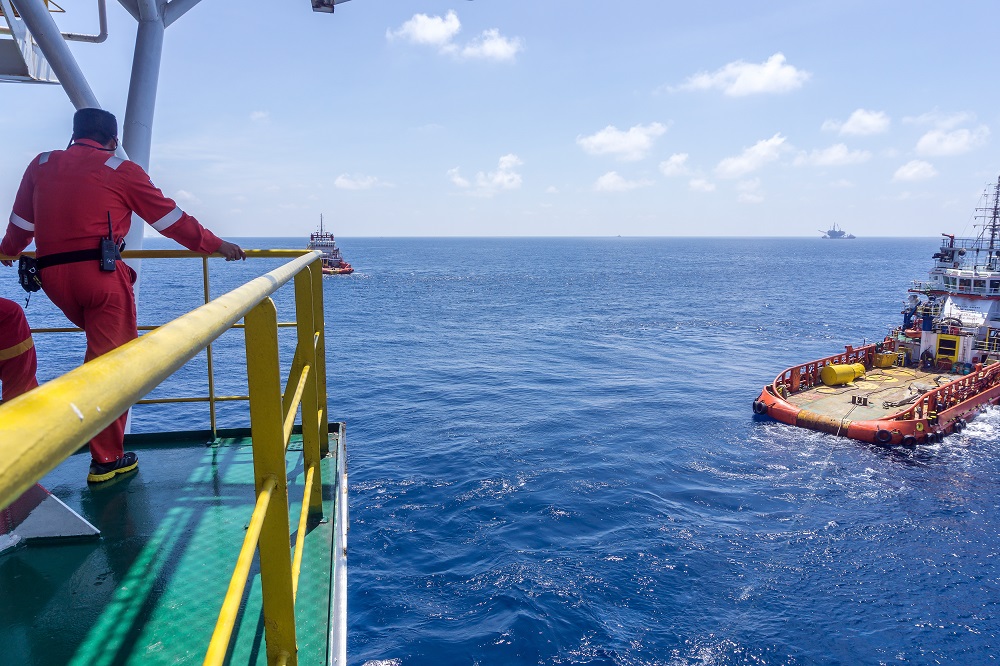 Man in uniform looking out over sea where boat is