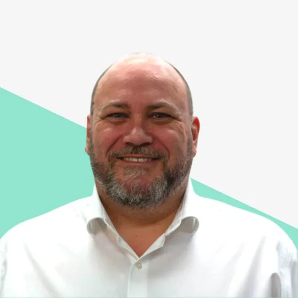 Smiling man with a beard against a light background.