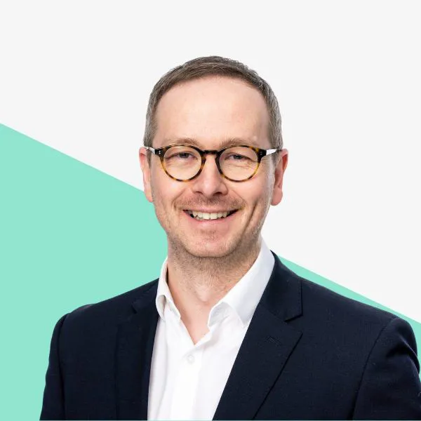 Smiling man in glasses against a light background.
