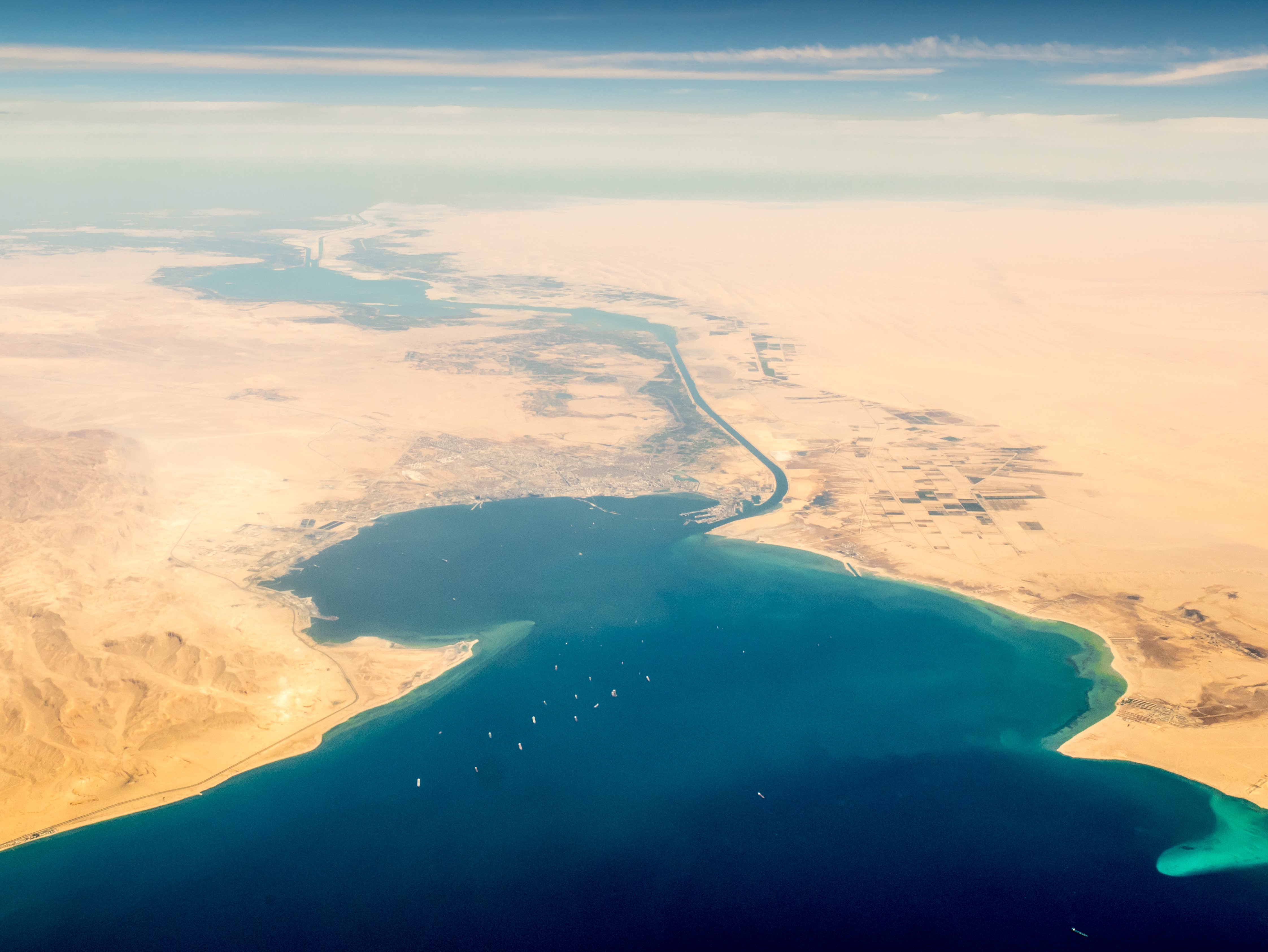 Aerial view of desert and blue water coastline.