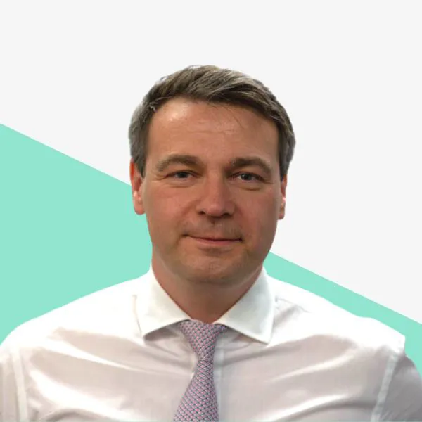 A man in a white shirt and tie against a colorful background.