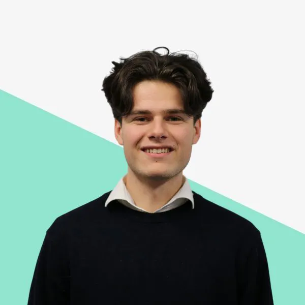 Smiling young man in a dark sweater against a geometric background.