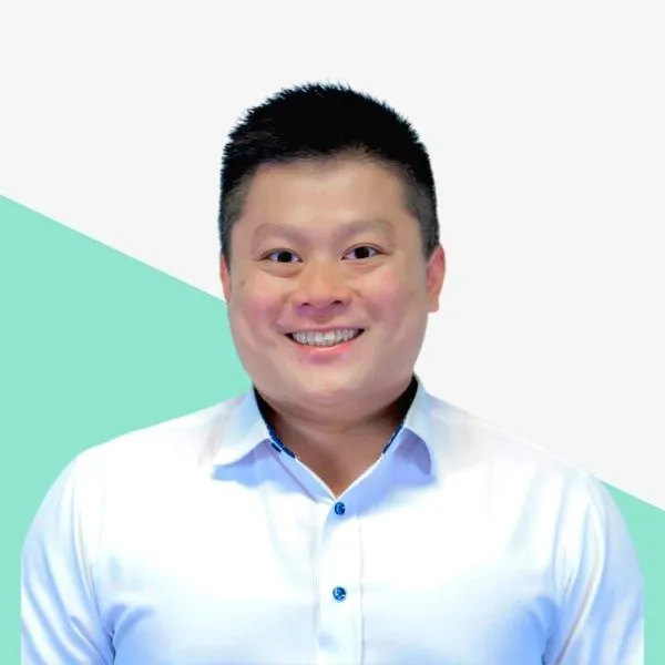 Smiling man in a white shirt, teal background.