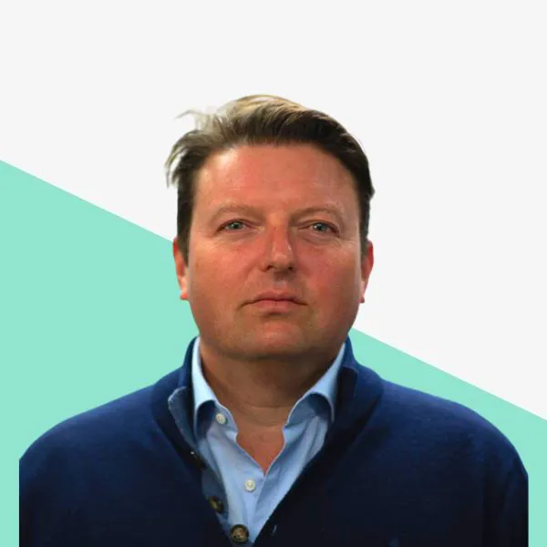 Man in a blue sweater against a light background.