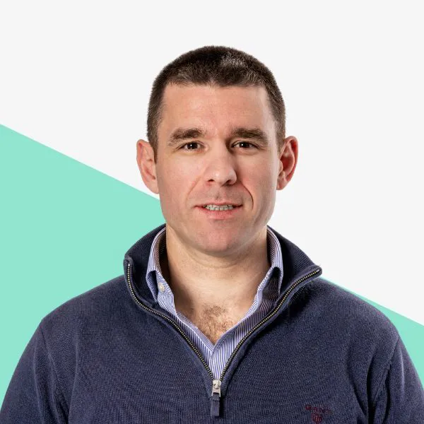 Man in a blue sweater against a light background.