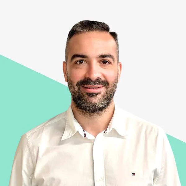 Smiling man in a white shirt with a mint background.