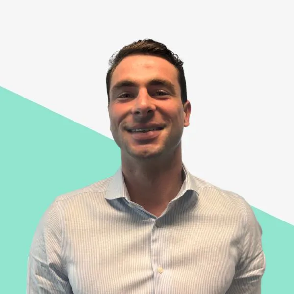 Smiling man in a light blue shirt on a colorful background.
