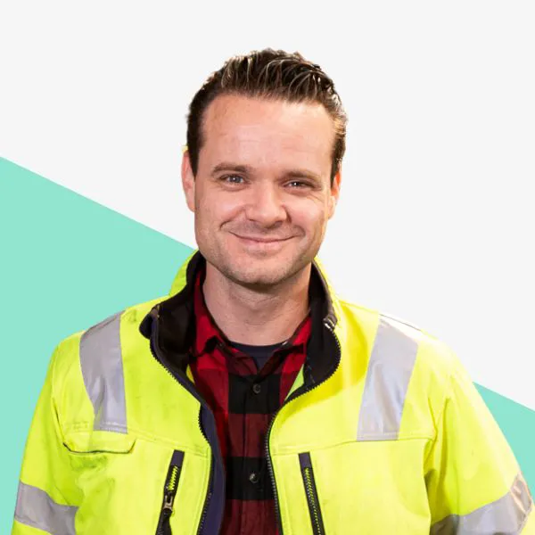 Man in a bright yellow safety jacket smiling.